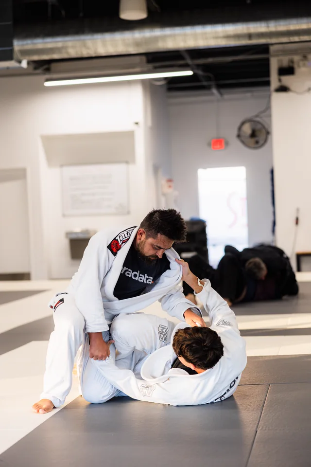Two students in white gis practice a grappling position